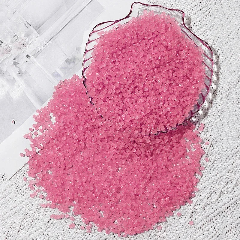 A pile of pink glow-in-the-dark decorative pebbles, some contained in a glass dish.