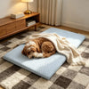 A fluffy golden dog is relaxing on a light blue, quilted ice silk cooling pet mat on a patterned rug.