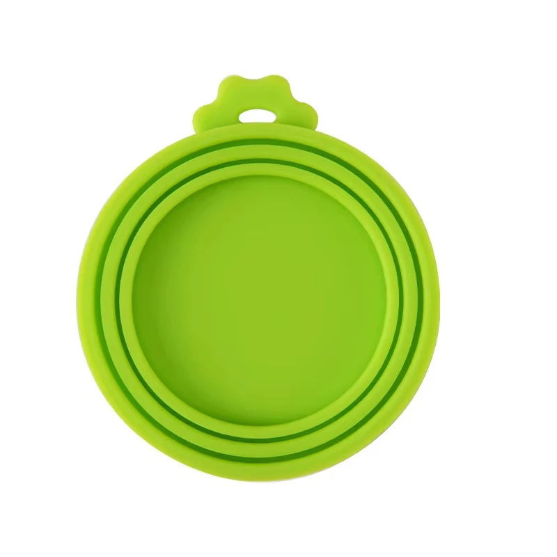A bright lime green reusable silicone pet food can lid with a spoon attachment.