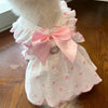 A white pet dress for a dog featuring pink polka dots and a pink bow collar.