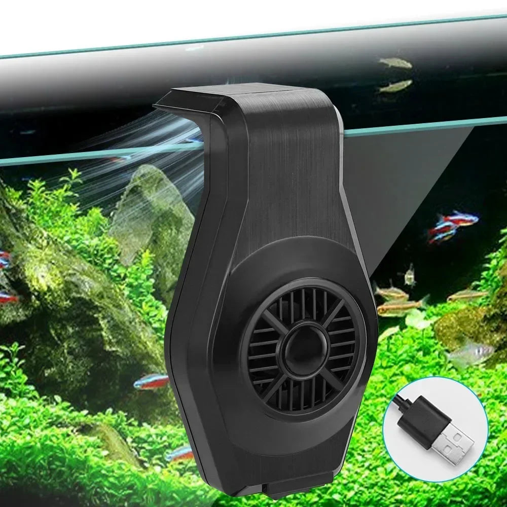 A black USB aquarium cooling fan is shown in a close-up against a background of lush green aquatic plants and rocks.