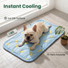 A light-colored dog lying on a blue mat with yellow banana patterns, demonstrating instant cooling for pets.