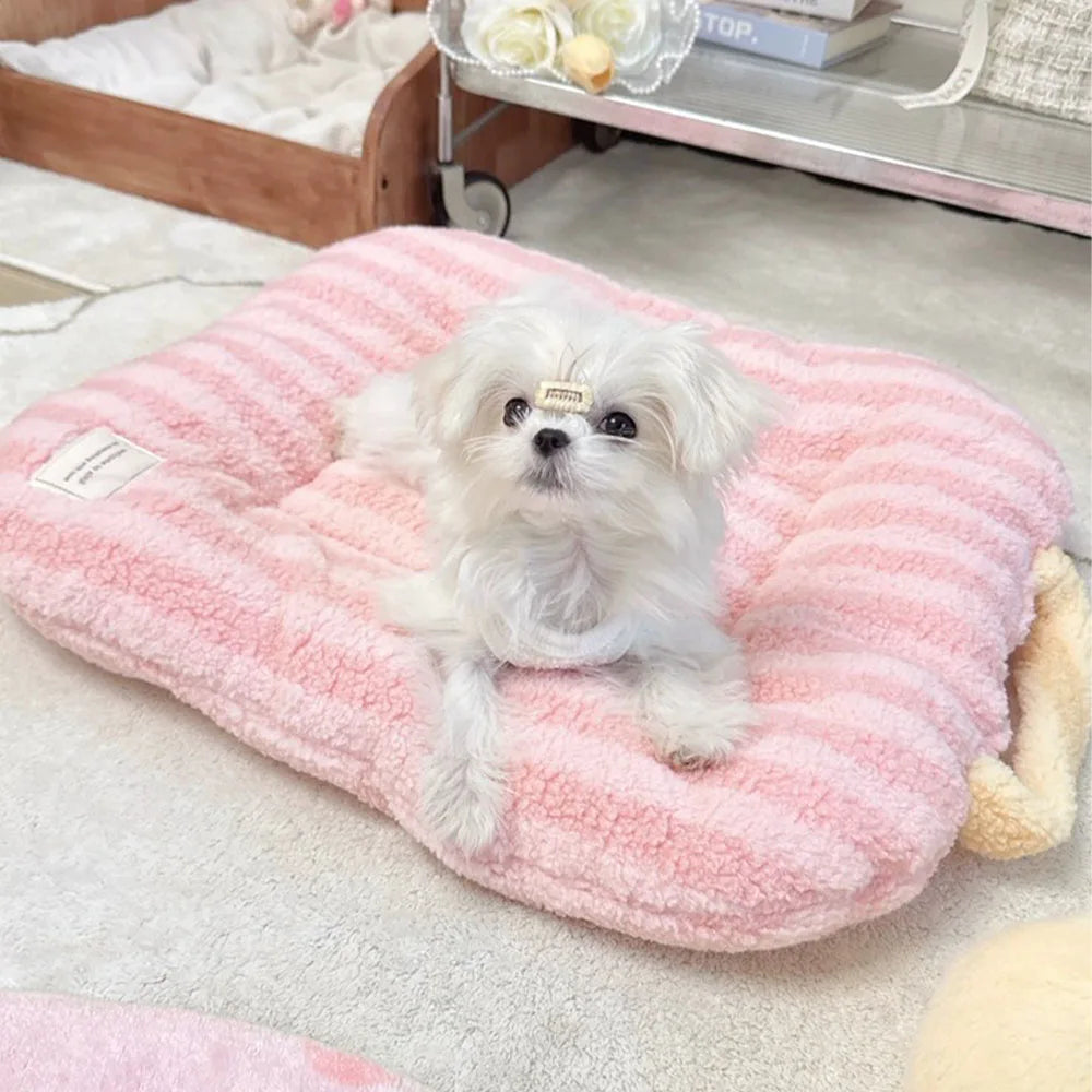 A fluffy white dog lies on a pink ribbed pet bed mat on a light-colored surface.