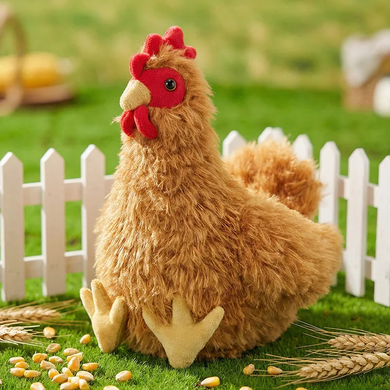 A lifelike plush rooster and hen set with brown feathers sitting on green grass surrounded by wheat stalks.