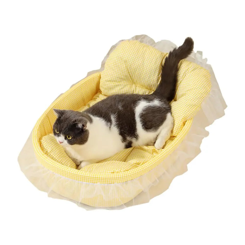 A black and white tabby cat is resting inside a yellow lace-trimmed plush pet sofa bed.
