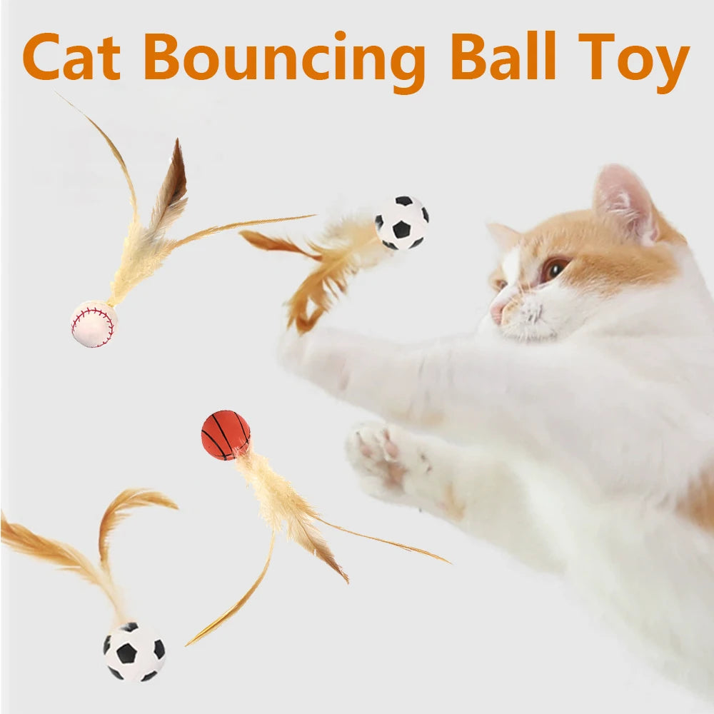 A cat is batting at three feather bouncy balls, including a soccer ball and a red ball.