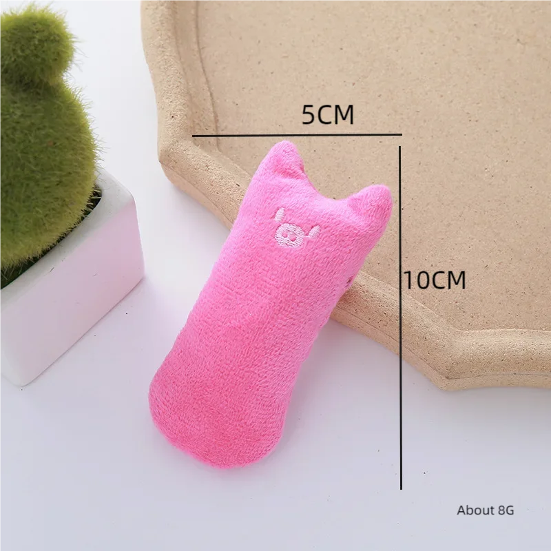 Pinke katzenförmige Plüschspielzeug neben einem Kaktus auf einem Holzbrett.