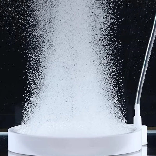A white air stone is creating a fine mist of bubbles over a clear container.
