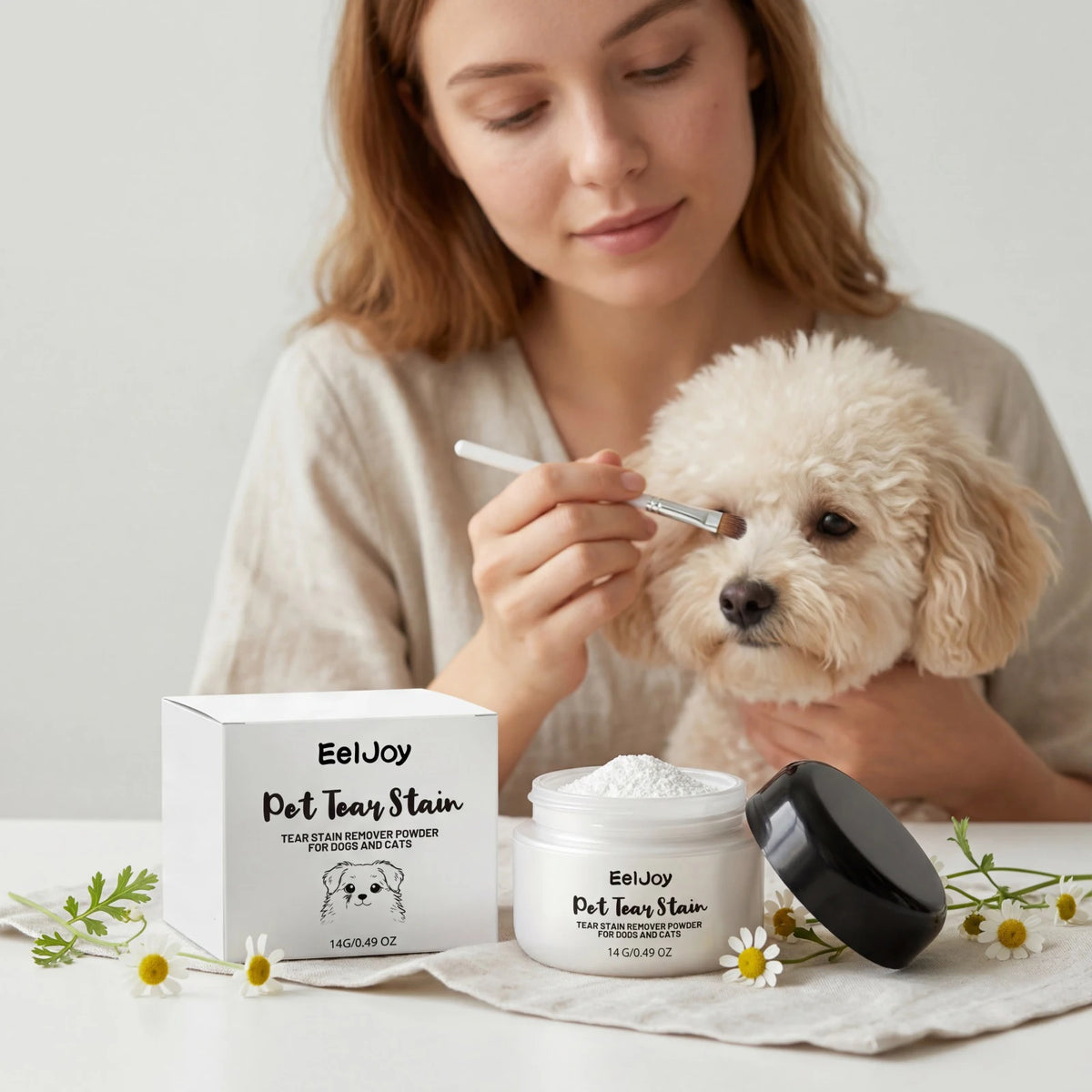 A woman is applying EelJoy Pet Tear Stain Remover Powder for dogs and cats to a small dog.