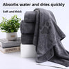 A stack of thick gray pet bath towels next to a potted plant and books.