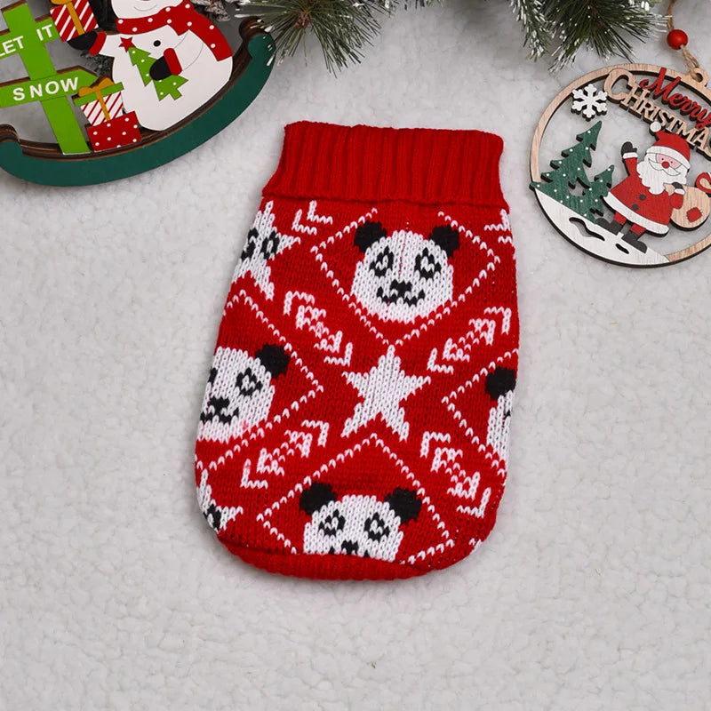 A knitted red sweater with white panda patterns and a ribbed cuff, displayed next to a Christmas ornament.