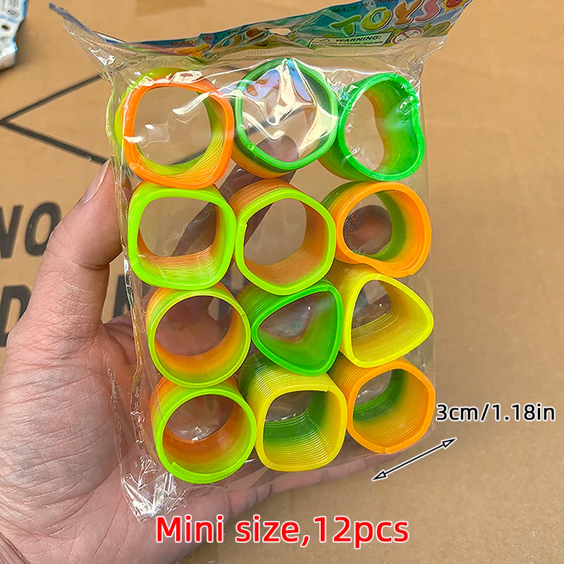 A hand holds a clear plastic bag containing 12 colorful spring coil toys in shades of orange and green.