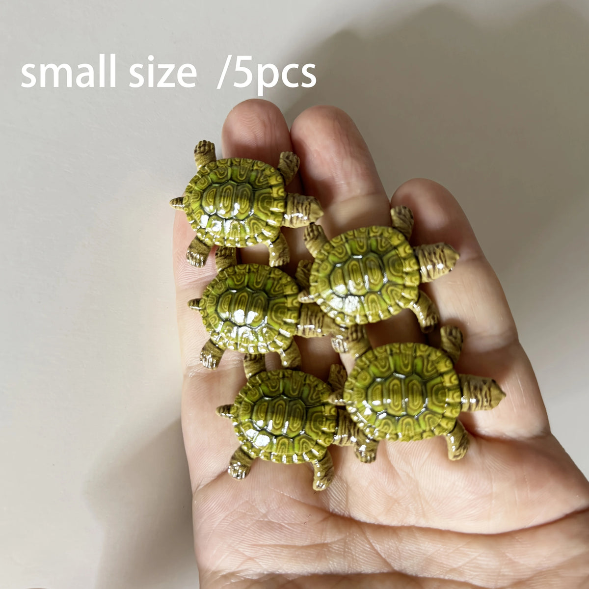 Five small green turtle ornaments are held in a person's hand.