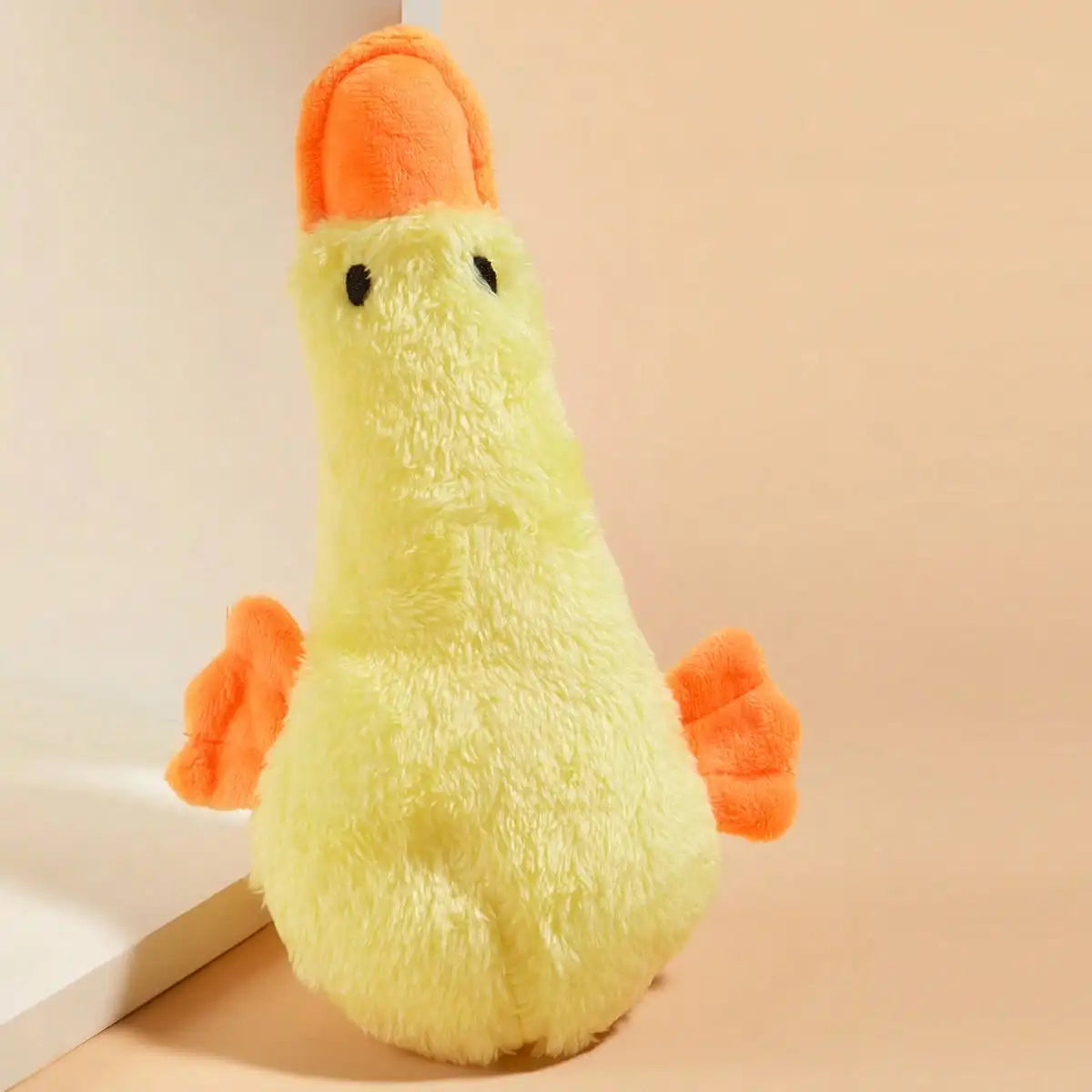 A yellow plush toy shaped like a duck with orange accents, sitting on a light surface.