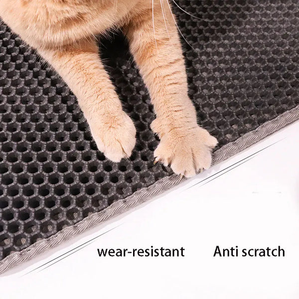 A close-up of a tan cat paw resting on a dark gray, honeycomb-textured litter mat.