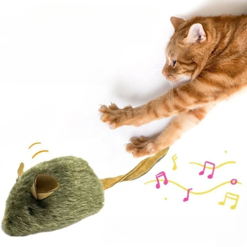 An orange tabby cat is playfully batting at a green plush mouse toy with musical notes scattered around it.