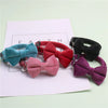 A collection of plush velvet pet collars featuring various colored bows including teal, red, black, and purple.