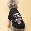 A fluffy dog wearing a black t-shirt with white text that reads I Give Free Kisses