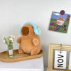 Braunes Capybara-Plüschtier mit hellblauen Akzenten neben einer gerahmten Capybara-Illustration
