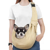 A light beige dog sling carrier with a black strap is worn by a person, featuring a small dog peeking out.