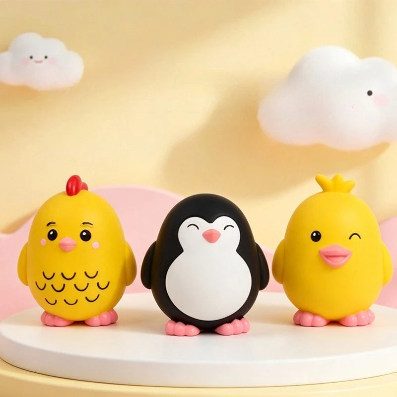 Three cute yellow duck and penguin dog toys sitting on a white surface with soft clouds in the background