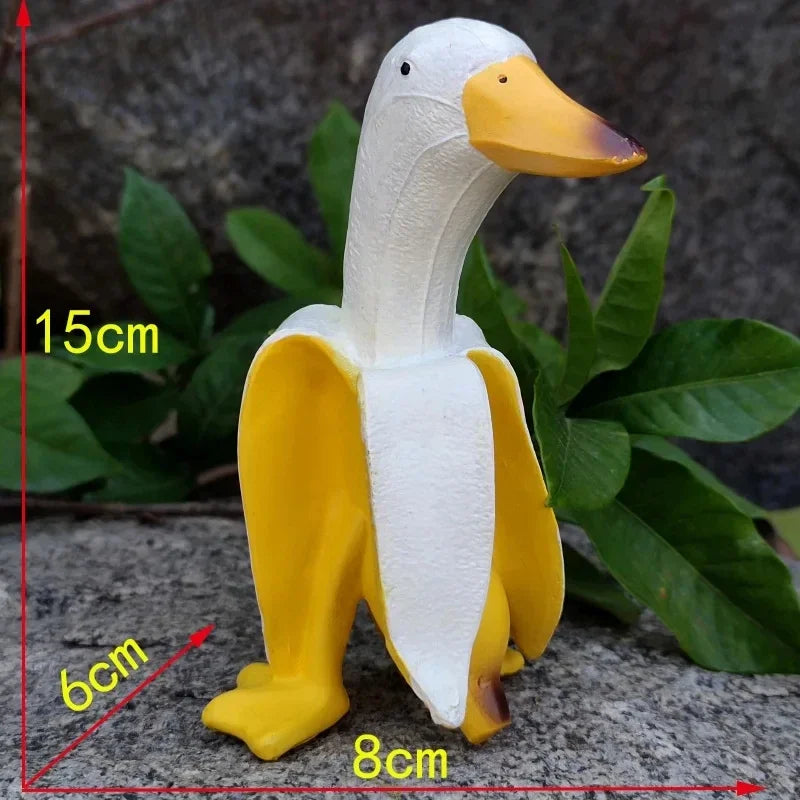 Weiße und gelbe Gartenskulptur einer Ente, die ihren Körper und Beine vor einem verschwommenen grünen Hintergrund zeigt.