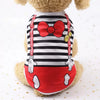 Un chien en peluche portant un gilet rayé noir et blanc avec un nœud rouge et des accents rouges.