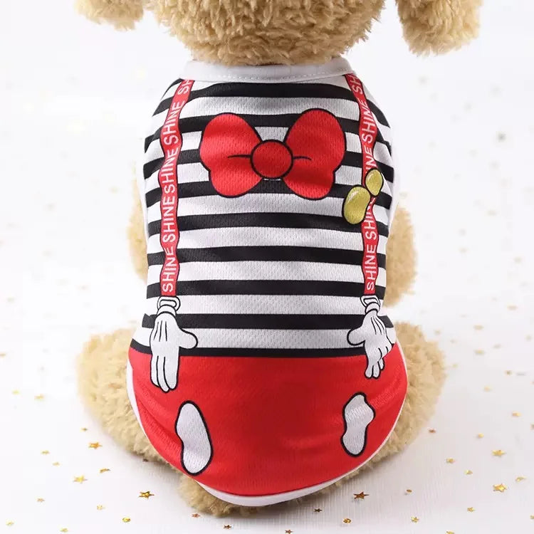 Un chien en peluche portant un gilet rayé noir et blanc avec un nœud rouge et des accents rouges.