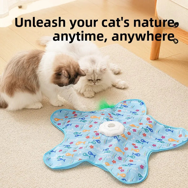 A fluffy white and gray cat is playing with a blue interactive teaser toy that has moving green feathers.