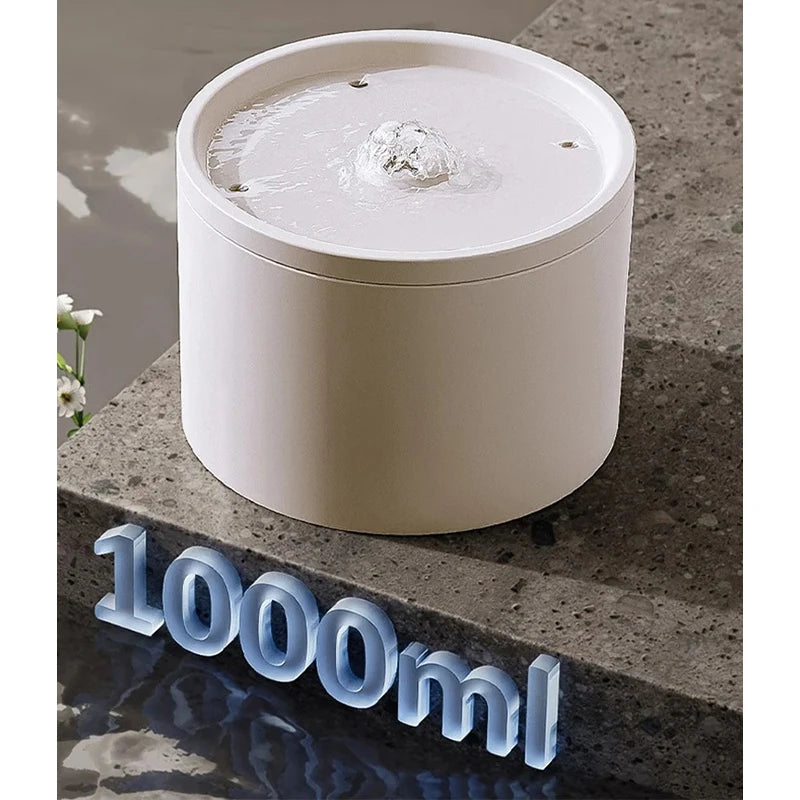 A white ceramic automatic pet water fountain is shown sitting on a gray stone surface.