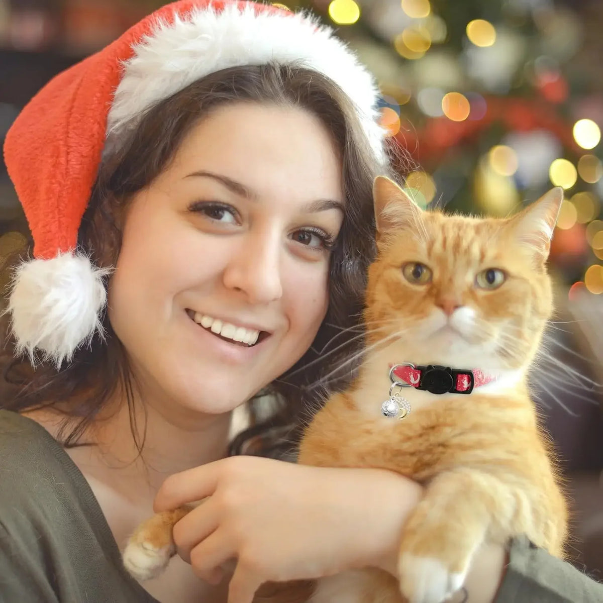 A young woman is holding an orange tabby cat wearing a glow-in-the-dark breakaway collar with a moon pendant and bell.