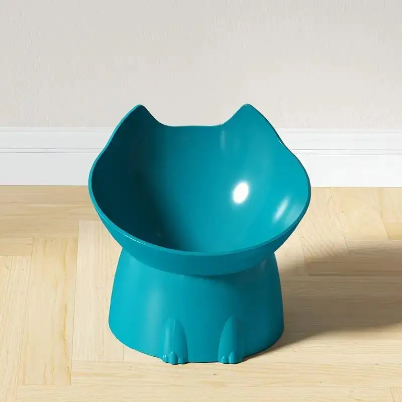 A teal elevated cat bowl with a storage and anti-tip base sitting on a light wooden floor.