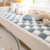 A cozy plush fleece pet bed mat with a diamond pattern in gray and white rests on a light-colored sofa.