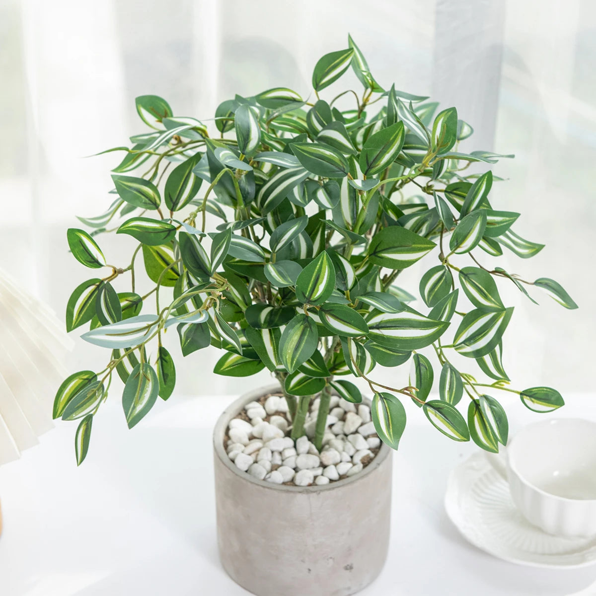 Artificial bonsai tree with green leaves in a pot, used for home and office decor.
