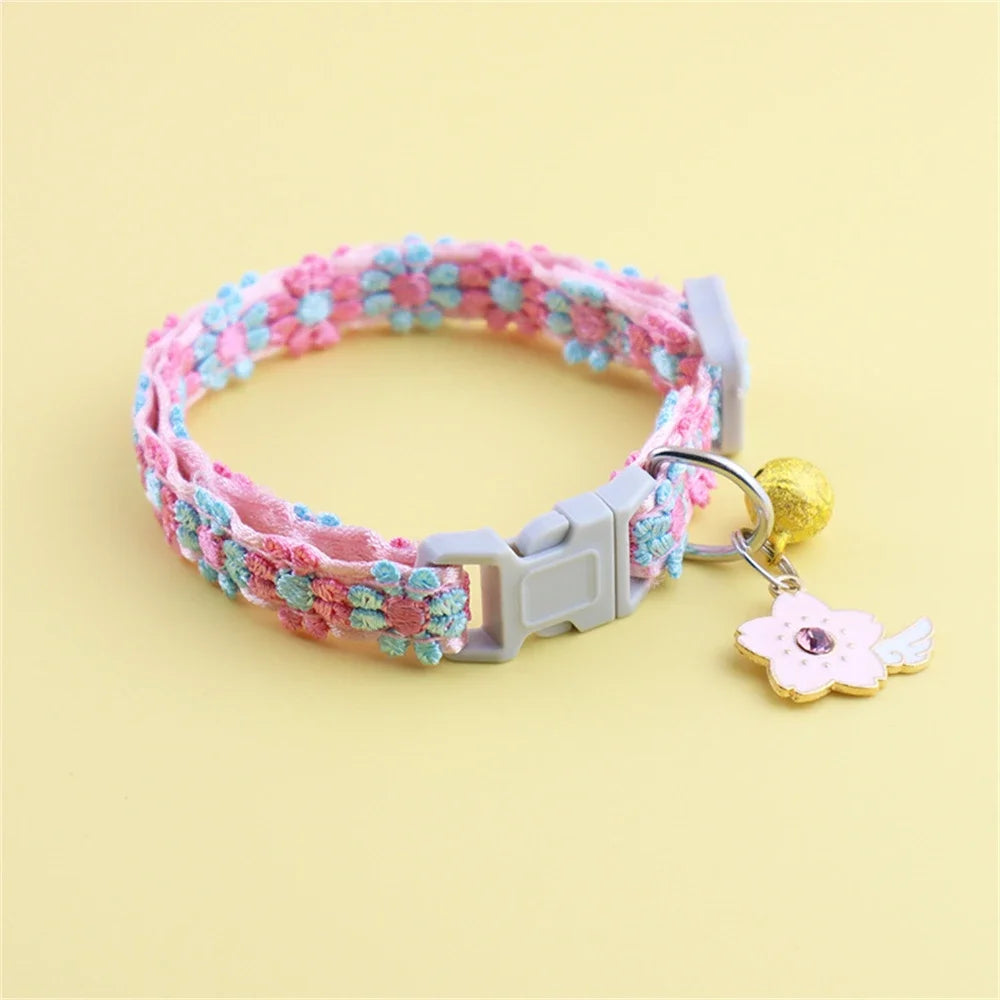 A pink and blue floral beaded collar with a silver buckle and a gold bell attached.