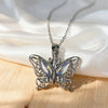 Silver butterfly ashes urn necklace displayed on white fabric and wooden surface