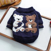 A navy blue knitted sweater featuring two embroidered teddy bears in white and brown on a wooden tray.