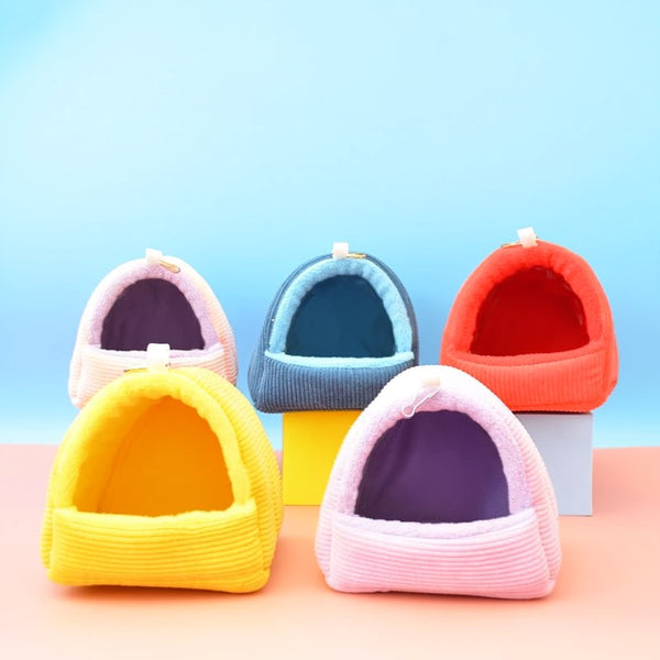 A collection of four soft, pink and orange fabric bird hammock nests displayed on a light pink surface.