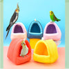 A collection of colorful, soft fabric bird hammocks and nests with small birds perched on them.