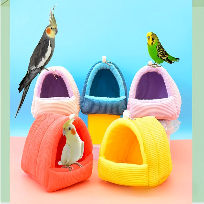 A collection of colorful, soft fabric bird hammocks and nests with small birds perched on them.