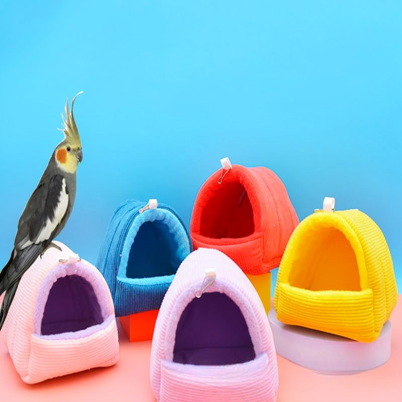 A collection of colorful, soft fabric bird hammocks or nests in pink, blue, orange, and yellow.