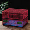 A red mesh bird cage cover is shown resting on a wooden surface.