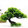 A miniature bonsai tree with bright green foliage is set on a light rock for aquarium or landscape decor.